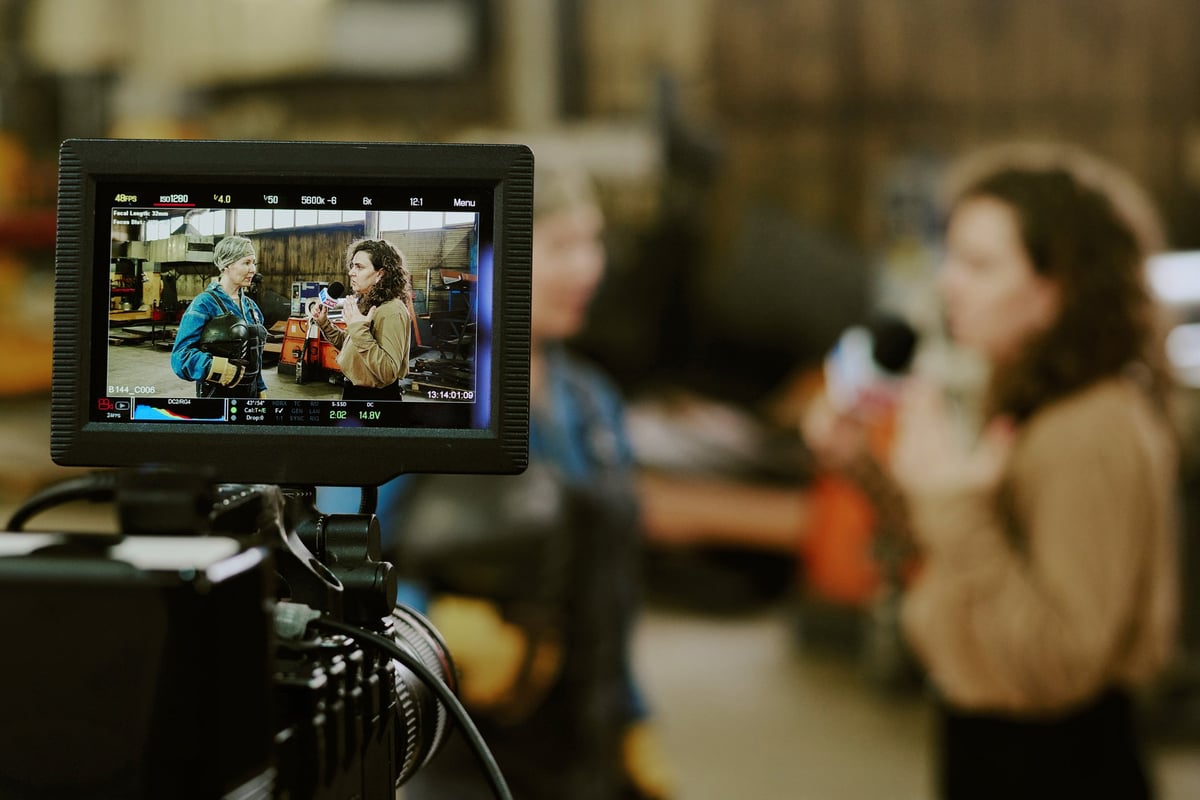 Professional camera filming two women in industrial workshop